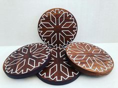 four wooden coasters with white designs on them