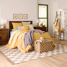 a bed room with a neatly made bed next to a wooden dresser and clock on the wall