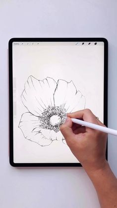 a person is drawing on a tablet with a white pen and black ink in front of them