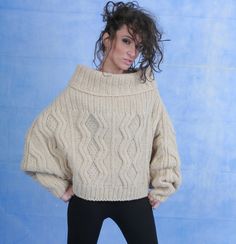 a woman in black pants and a white sweater posing for a photo with her hands on her hips