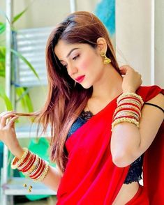 a woman in red sari and gold bracelets