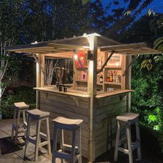 an outdoor bar with stools around it and lights shining on the outside area at night