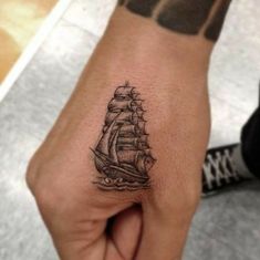 a hand with a small ship tattoo on it