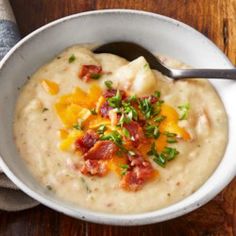 a white bowl filled with soup on top of a wooden table next to a spoon