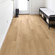 a wooden floor with a white door and black shoes on the bench next to it