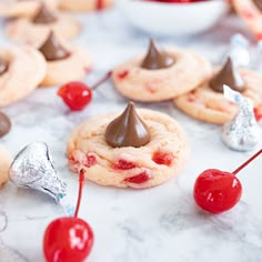 cookies with chocolate and cherries are on a table next to other desserts that include candy