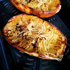 two squash halves with shredded parmesan cheese and herbs on the top, sitting in an air fryer