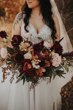 a woman in a wedding dress holding a large bouquet with red and pink flowers on it