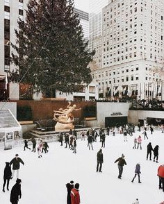 many people are skating on an ice rink in the middle of a large city square