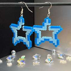 the earrings are made out of plastic and have blue squares on them, with small crystal beads