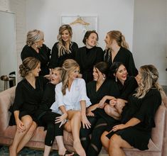 a group of women sitting on top of a pink couch in front of a mirror