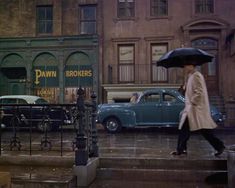 a woman walking down the street in the rain with an umbrella over her head,