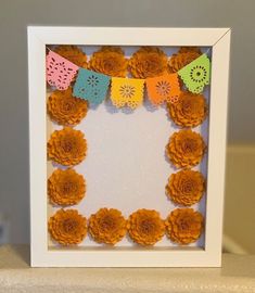 a white frame with paper flowers in it