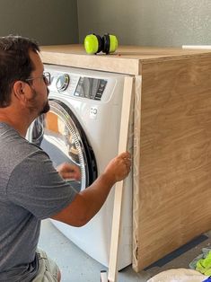 a man is working on a washer in a room that has been built into the wall