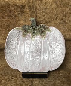 a white pumpkin shaped dish sitting on top of a brown cloth