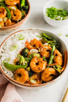 two bowls filled with shrimp, broccoli and rice on top of a table