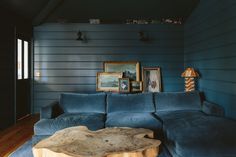 a living room with blue couches and pictures on the wall above it, along with a wooden coffee table