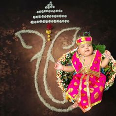 a baby is sitting on the ground in front of a sign that reads happy diwali