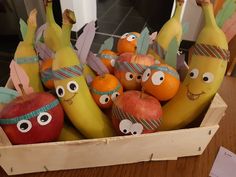 a box filled with bananas, apples and oranges decorated to look like cartoon characters