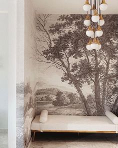 a room with a bed and wallpaper that has trees painted on the walls behind it