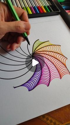 someone is drawing with colored pencils on paper