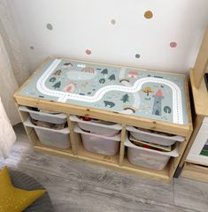 a child's play table with storage bins and toy cars on the floor