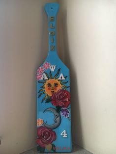 a wooden paddle with flowers painted on it and the number four is in front of a white wall