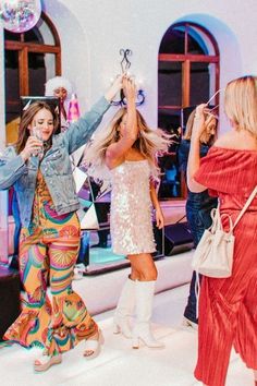 two women in dresses and boots are dancing on the dance floor with disco balls behind them