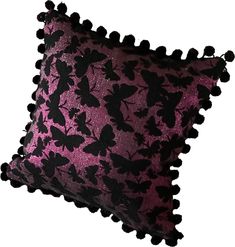 a pink and black pillow with pom poms