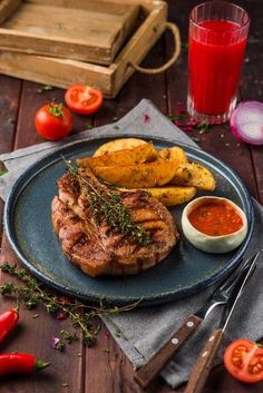 grilled steak and french fries on a blue plate with tomatoes, tomato sauce and knife