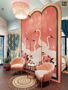 a living room with pink walls, chairs and a large painting on it's wall