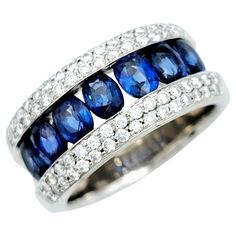 Ring Size: 6.25 This captivating band ring is a sophisticated and stunning work of art. Crafted with precision, the ring features a series of exquisite oval blue sapphires channel-set between delicate pave diamonds, creating a harmonious blend of color and sparkle. The meticulous arrangement of stones ensures a seamless, flowing design, while the polished finish of the remaining band enhances the overall allure. The blue sapphires, with their timeless allure, evoke a sense of regality and charm, Luxury Multi-stone Oval Sapphire Ring, Luxury Sapphire Channel Set Ring, Luxury Sapphire Rings Channel Set, Luxury Oval Diamond Ring With Channel Set, Modern Gia Certified Oval Rings, Modern Oval Gia Certified Rings, Elegant Multi-stone Wide Band Rings, Elegant Oval Rings With Channel Set, Fine Jewelry Oval Diamond Ring Channel Set