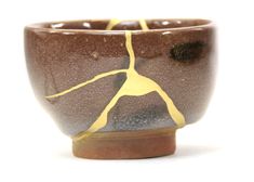 a brown and white bowl with yellow lines on the inside, sitting on a white surface