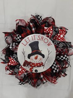 a red and black wreath with a snowman on it that says let it snow