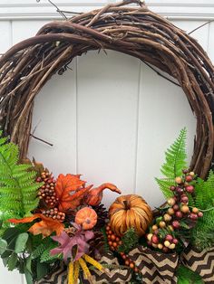 a wreath with leaves, berries and acorns hanging on the front door for fall