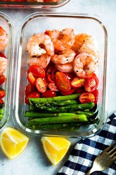 two plastic containers filled with shrimp, asparagus and cherry tomatoes next to lemon wedges