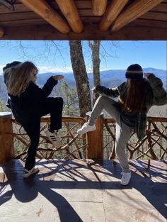 two people doing tricks on a deck in front of some trees with mountains in the background