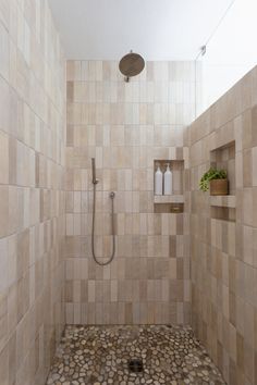 a walk in shower sitting next to a tiled wall