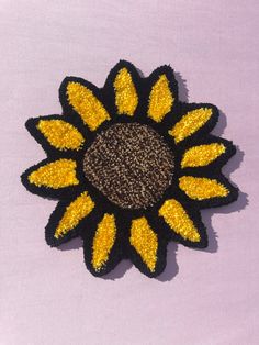 a black and yellow brooch sitting on top of a purple surface