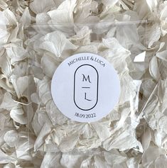 a round sticker with the letter m on it surrounded by white paper flowers and leaves