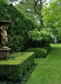 a garden with hedges and statues in it