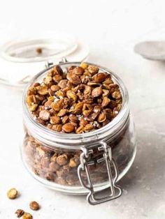 a glass jar filled with nuts next to spoons