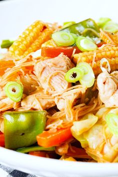 a white bowl filled with chicken and veggies on top of a checkered table cloth