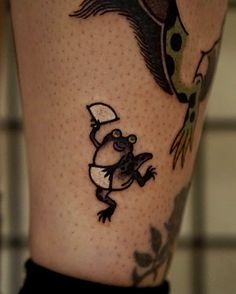 a tattoo on the leg of a person with a hat and frog holding a tennis racquet