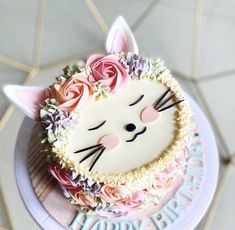 a birthday cake decorated with flowers and a cat face