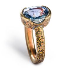 "This beautiful and unique Mokume Gane engagement ring is shown in the Droplet pattern and the Fire metal combination and features a partial mokume bezel with a lovely oval shaped blue sapphire. The Fire palette features 14k yellow gold, 14k red gold and sterling silver. Palette: Fire Pattern: Droplet Width Shown: 3mm Size Shown: 5 Finish: Etched & Oxidized Profile: Low Dome Stone: Oval Blue Sapphire Price does NOT include stones or setting fees, and price varies according to width of band. Hand Forged Oval Sapphire Ring For Anniversary, Blue Hand Forged Rings For Anniversary, Hand Forged Blue Rings For Anniversary, Hand Forged Blue Rings For Wedding, Gold Sapphire Cabochon Ring, Mokume Gane Rings, Mokume Gane Earrings, Unique Orange Cabochon Ring, Mokume Gane Ring