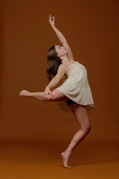 a woman in a white dress is doing a dance move with her leg up and one hand behind her head