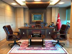 two brown chairs sitting in front of a desk with a flag on top of it