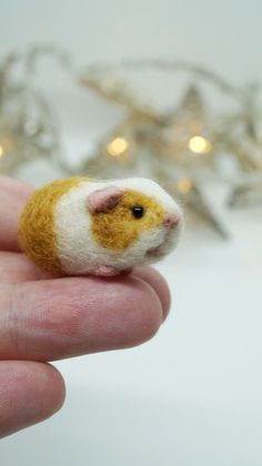 a tiny toy hamster is sitting in someone's hand