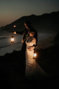 a bride and groom holding lanterns in the dark